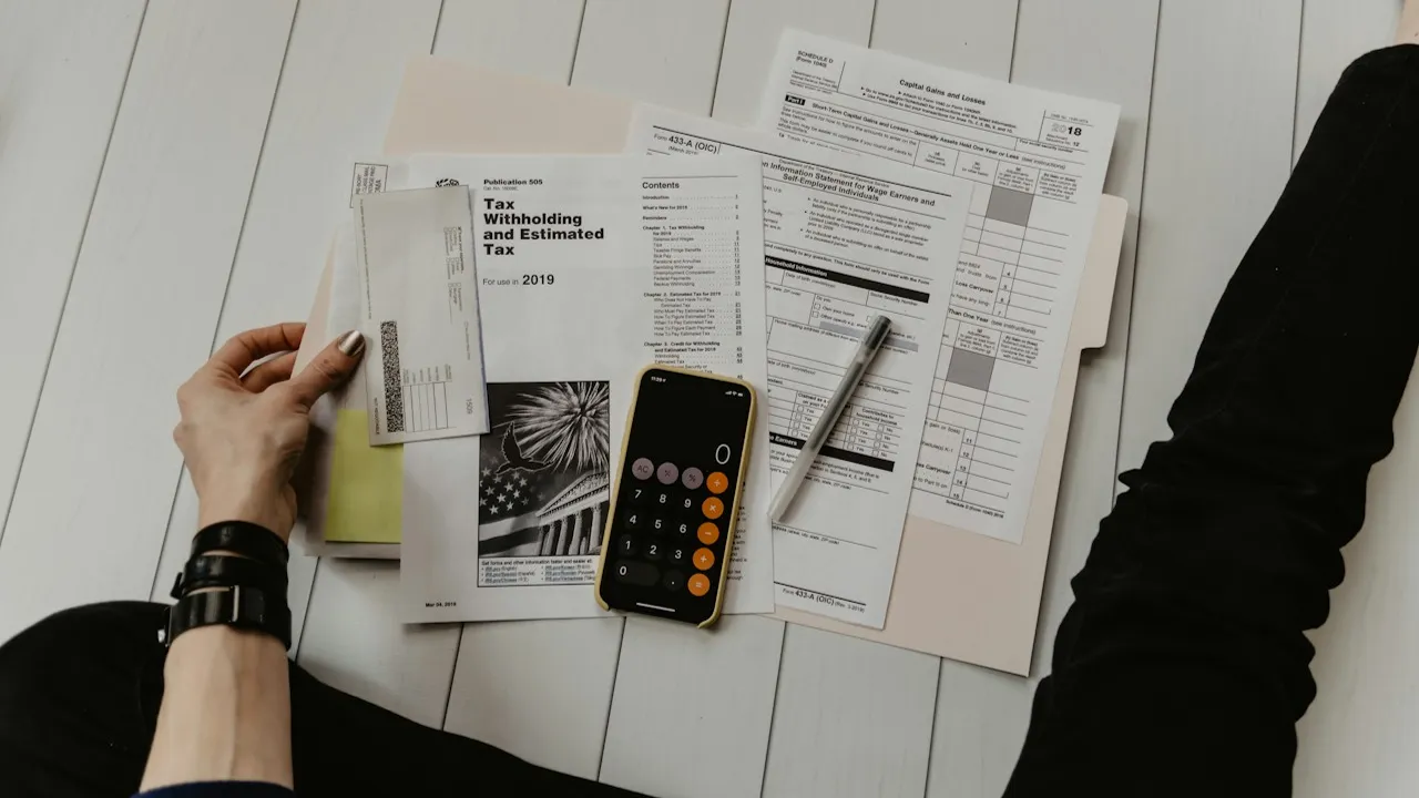 Hands reviewing bills beside a calculator on a white table